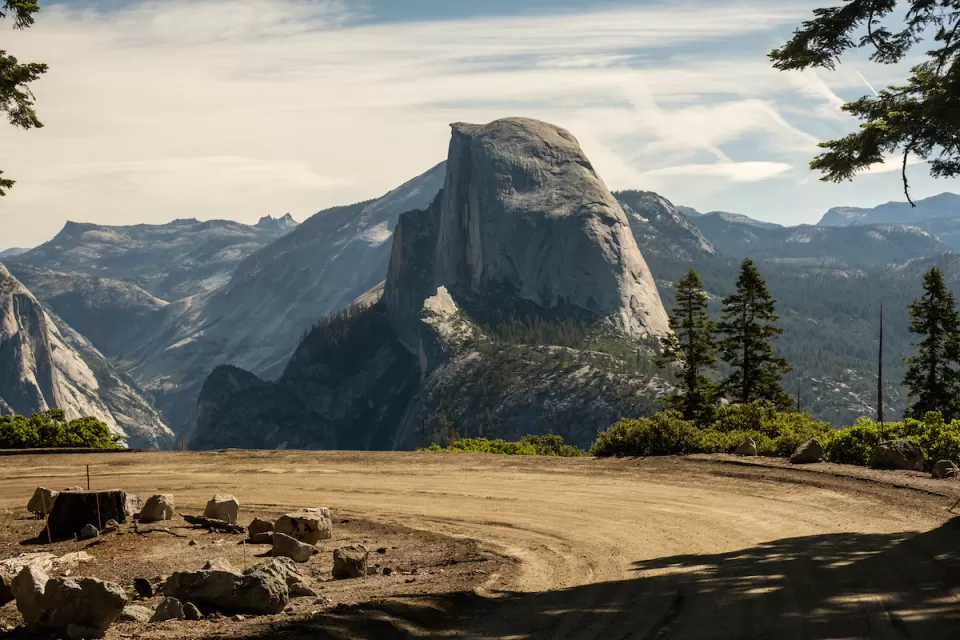 A dirt road turns int he foreground while Half Dome looms majestically in the background.